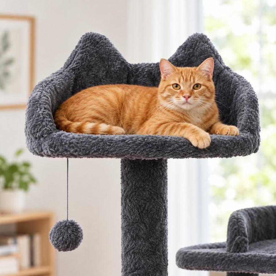 Cat lying in the padded cat-ear top perch above a dangling pom-pom ball